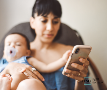 woman holding baby looking at her phone