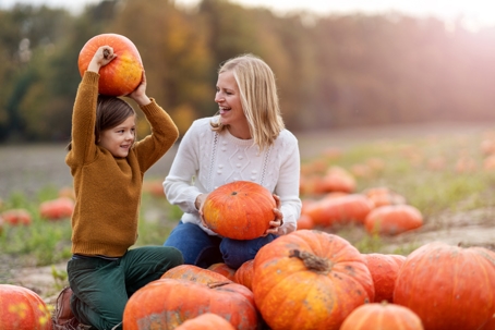mother and child playing in pumpkin patch