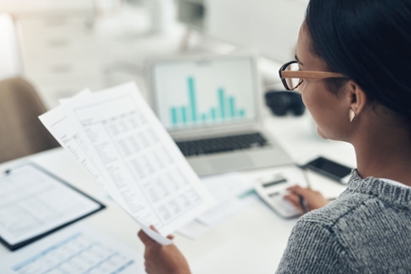 A woman reviewing bank statements and important financial documents in her office.