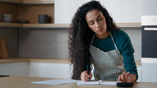 mother calculating expenses on kitchen counter