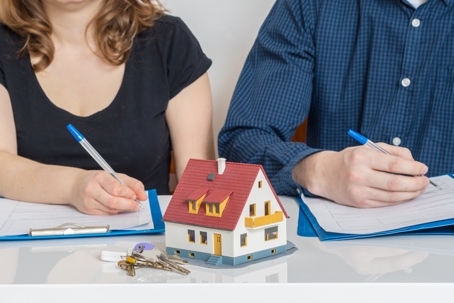 couple signing divorce papers with figure of a house between them